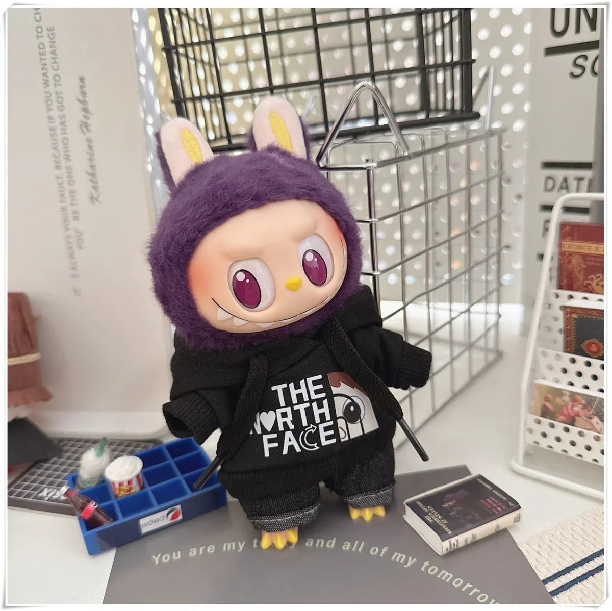 Plush toy with a purple hood and black 'The North Face' jacket on a desk.