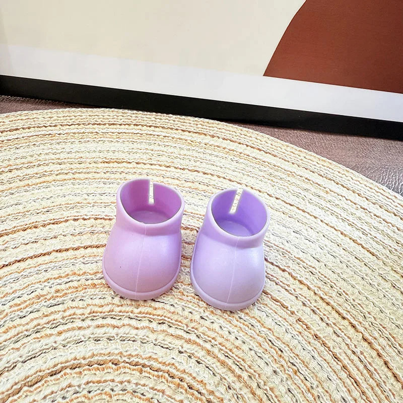 Two purple silicone boot-shaped candles on a textured surface.
