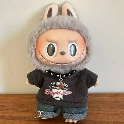 Plush toy with a gray outfit and rabbit ears on a wooden surface.