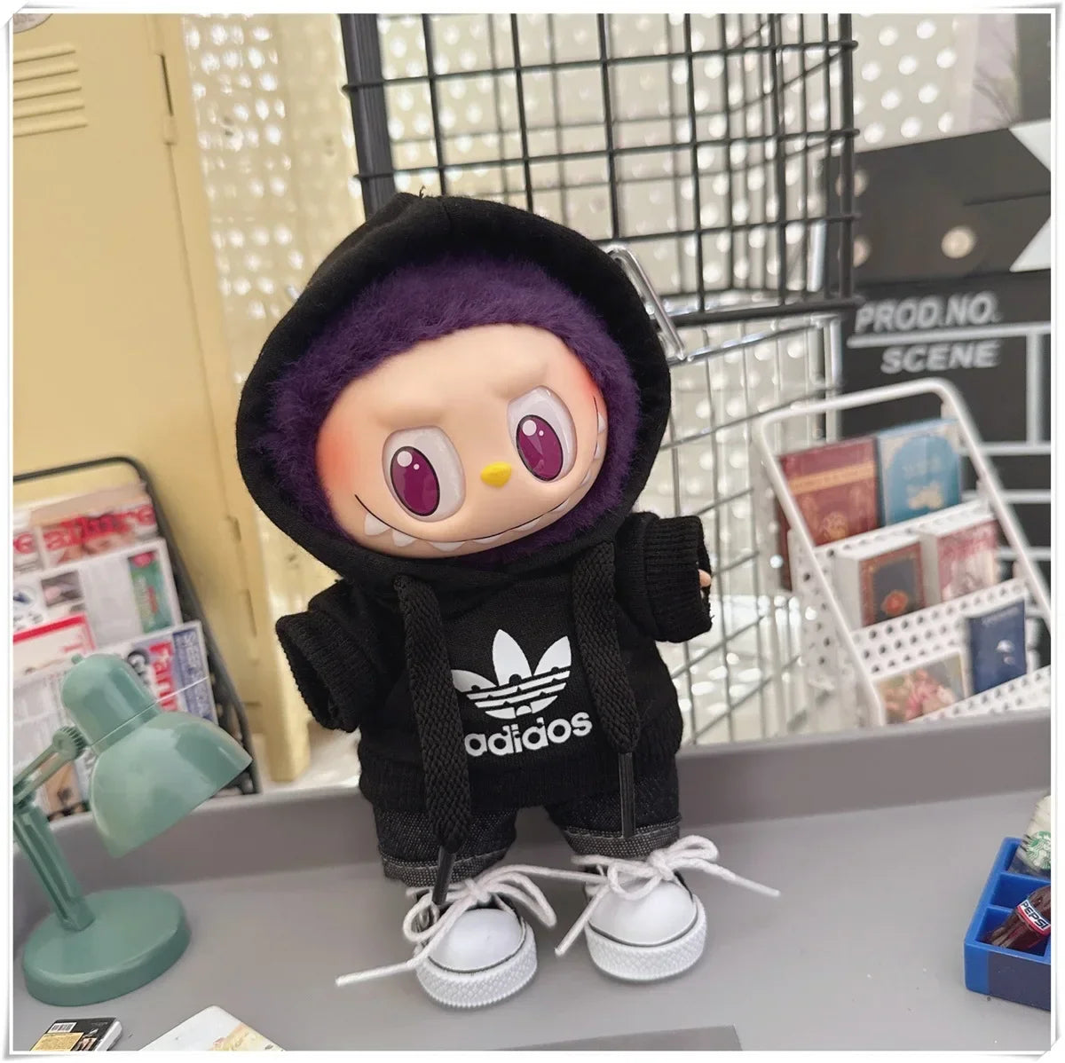 Plush toy with a black hoodie featuring Adidas logo on a desk.
