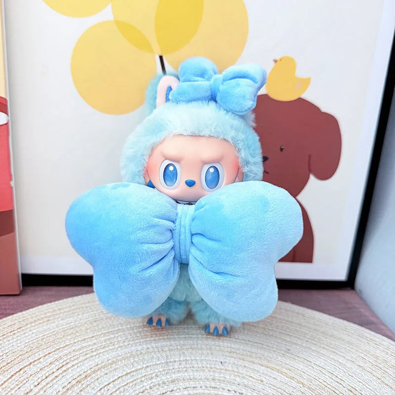 Blue plush toy with a large bow on a textured surface with colorful abstract art in the background.