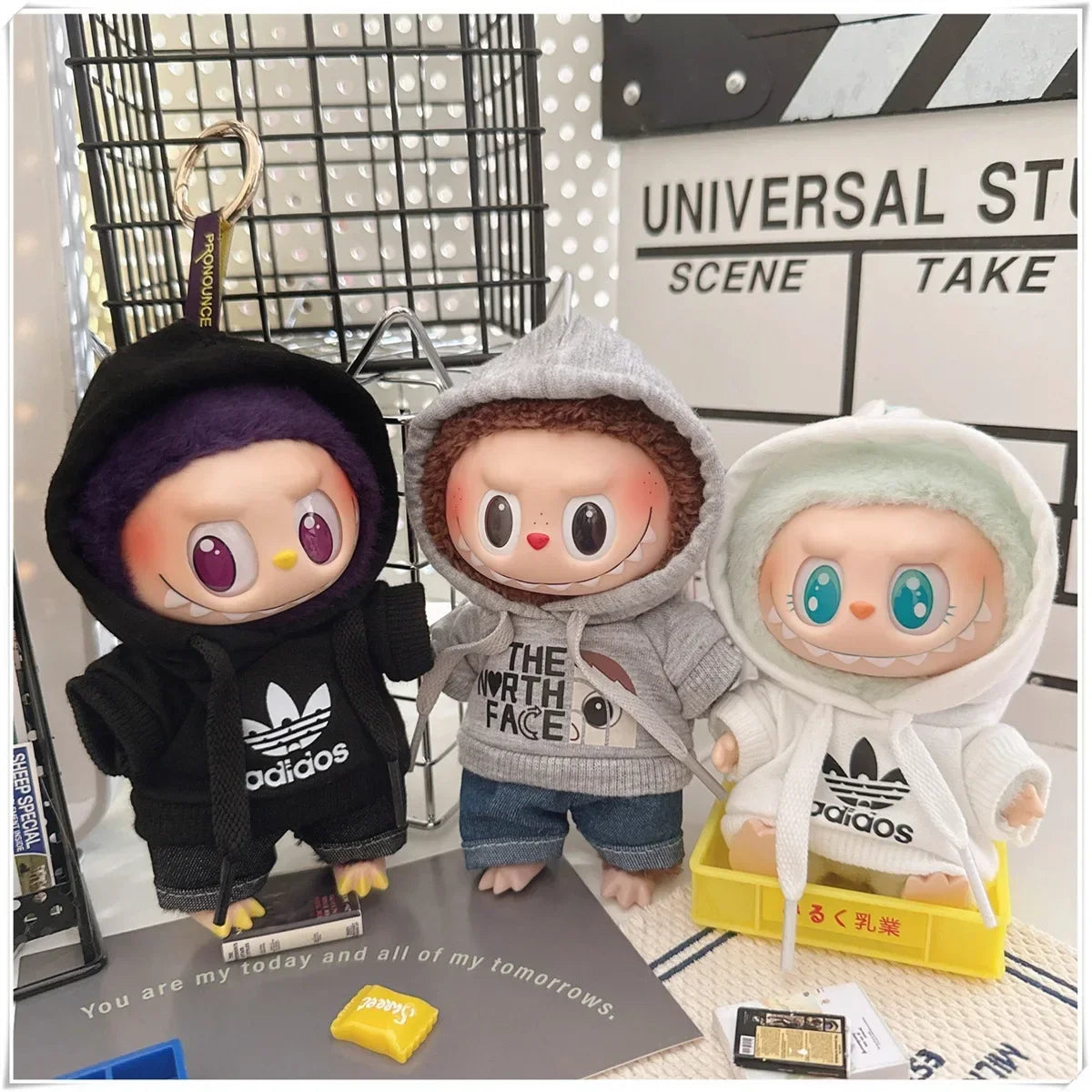 Three plush toys wearing hoodies with visible brand logos on a surface.