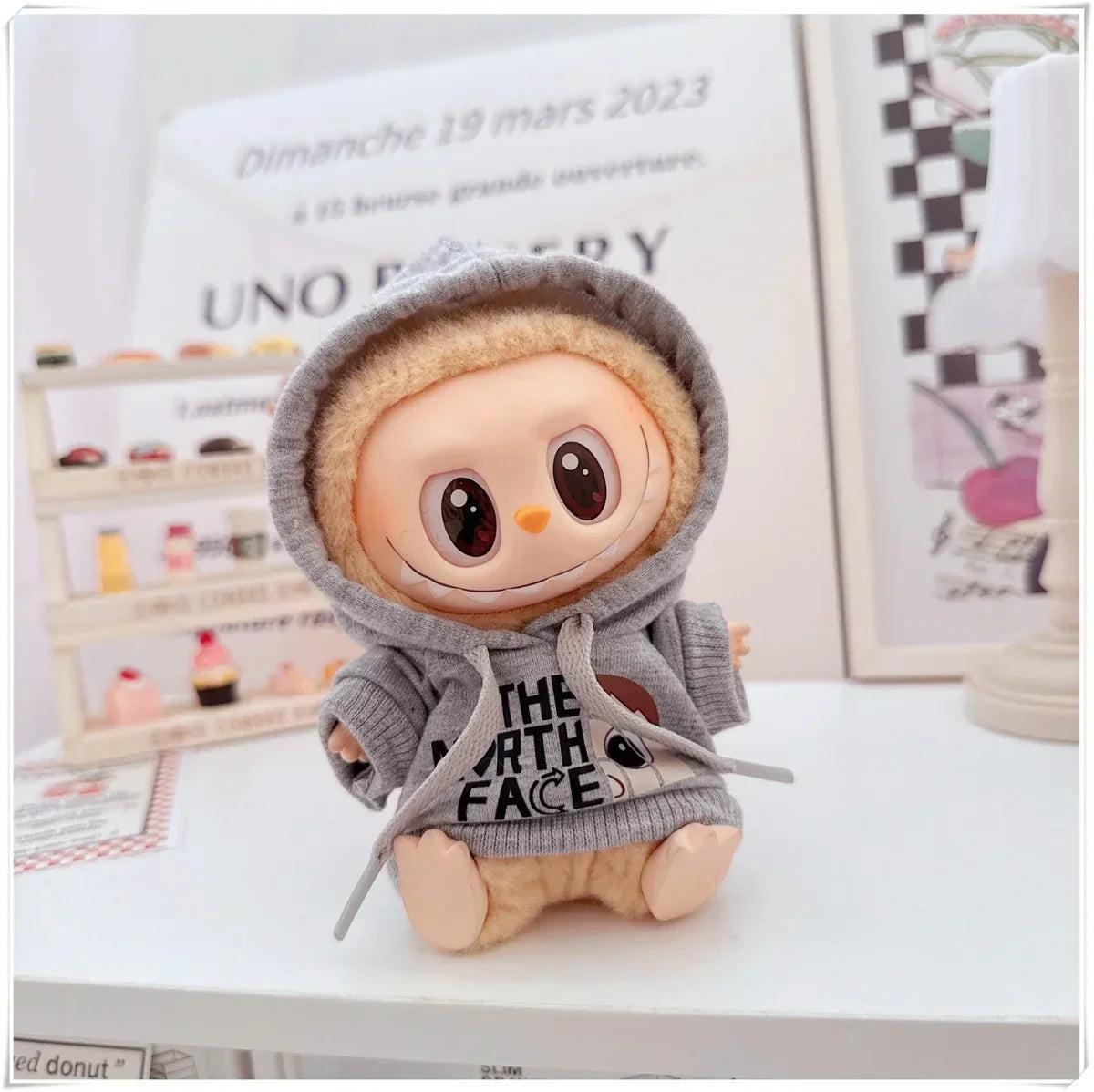 Plush toy with a gray hoodie on a white surface
