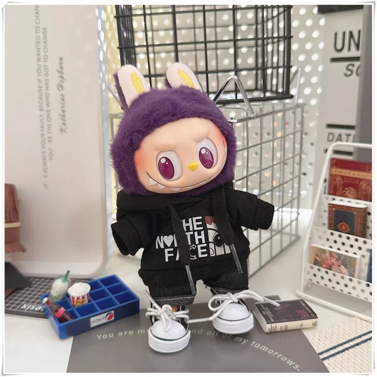 Plush toy with a purple hood and black outfit on a desk