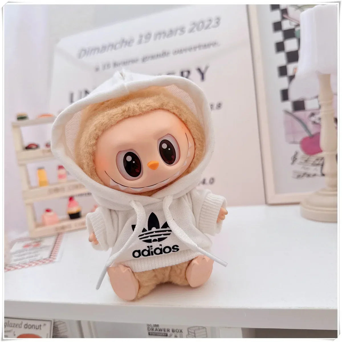 Plush toy with Adidas hoodie on a surface with a blurred background