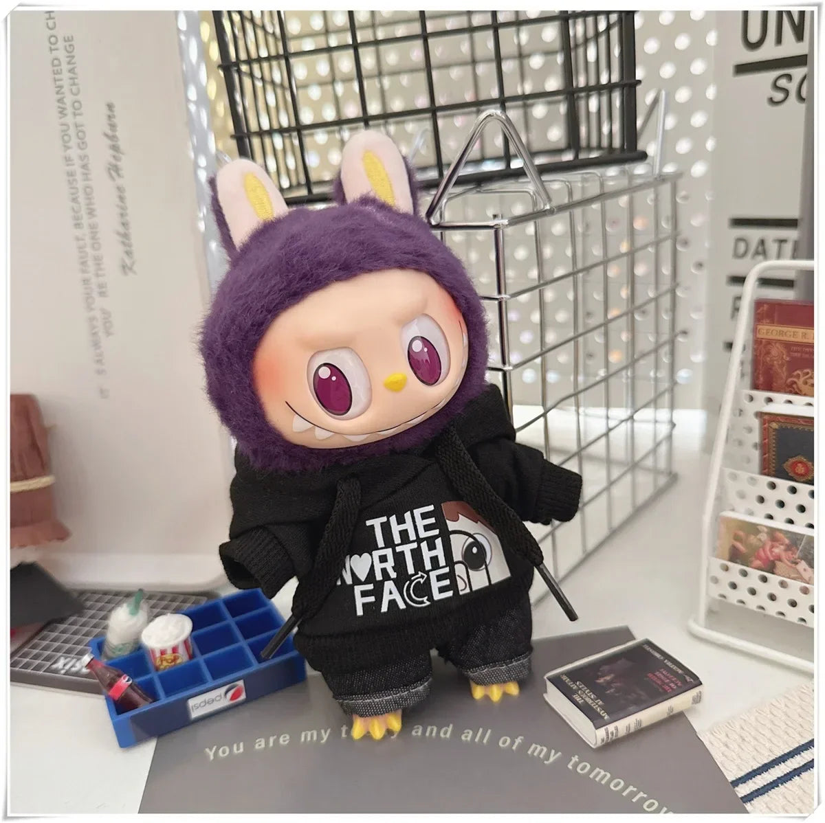 Plush toy with a purple hood and black 'The North Face' jacket on a desk.