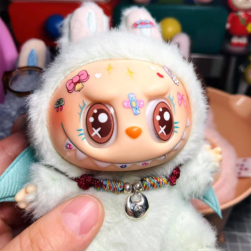 Plush toy with cartoon face and colorful necklace held by a hand