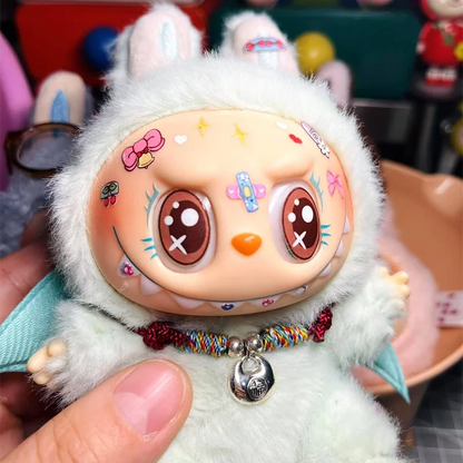 Plush toy with cartoon face and colorful necklace held by a hand
