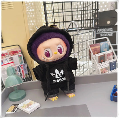 Toy figure wearing an Adidas hoodie on a desk with a magazine and lamp in the background