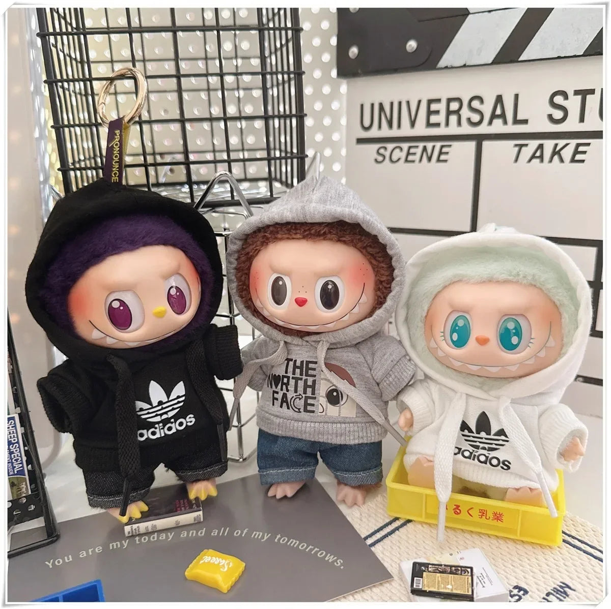 Three plush toys wearing hoodies with visible brand logos on a surface.