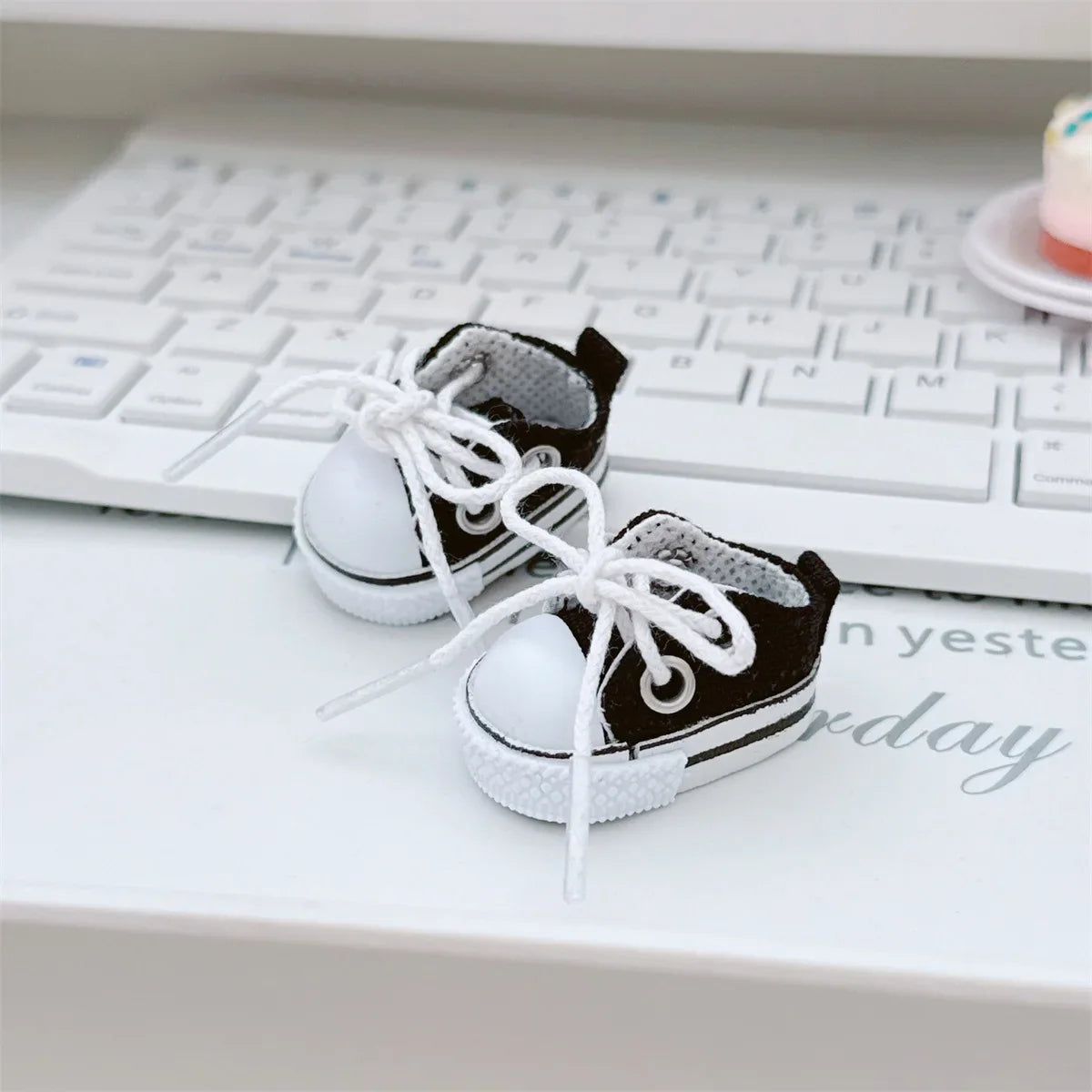 Pair of black and white baby shoes on a desk with a keyboard in the background