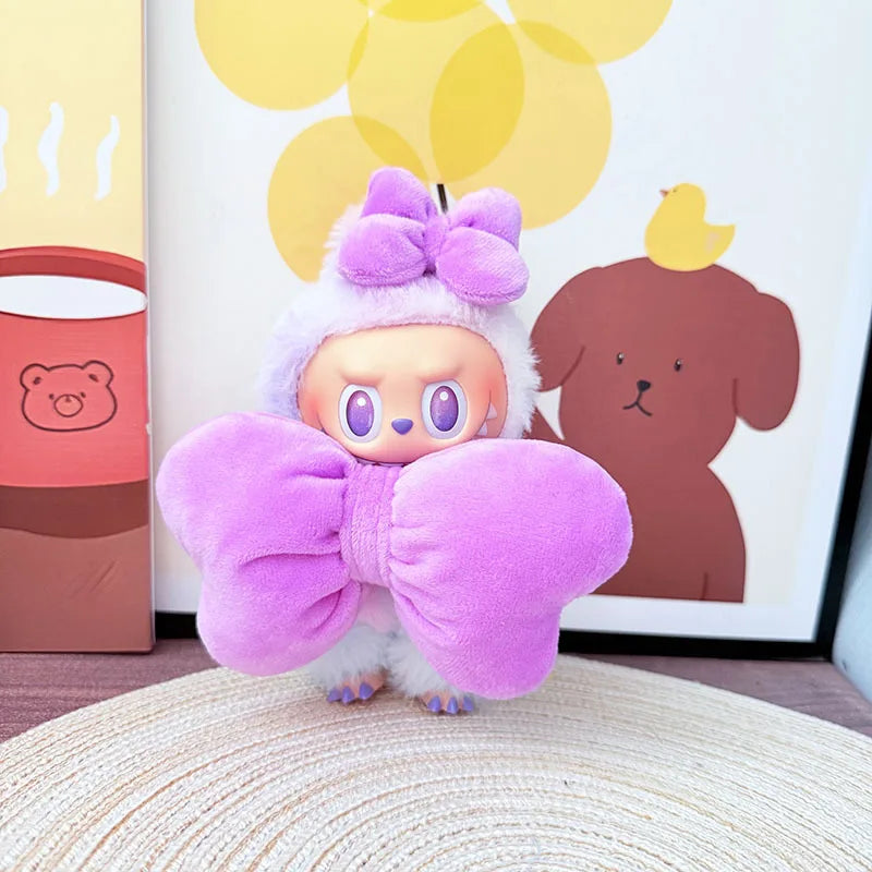 Plush toy with large purple bow in front of a framed picture of a dog and a pink bucket.