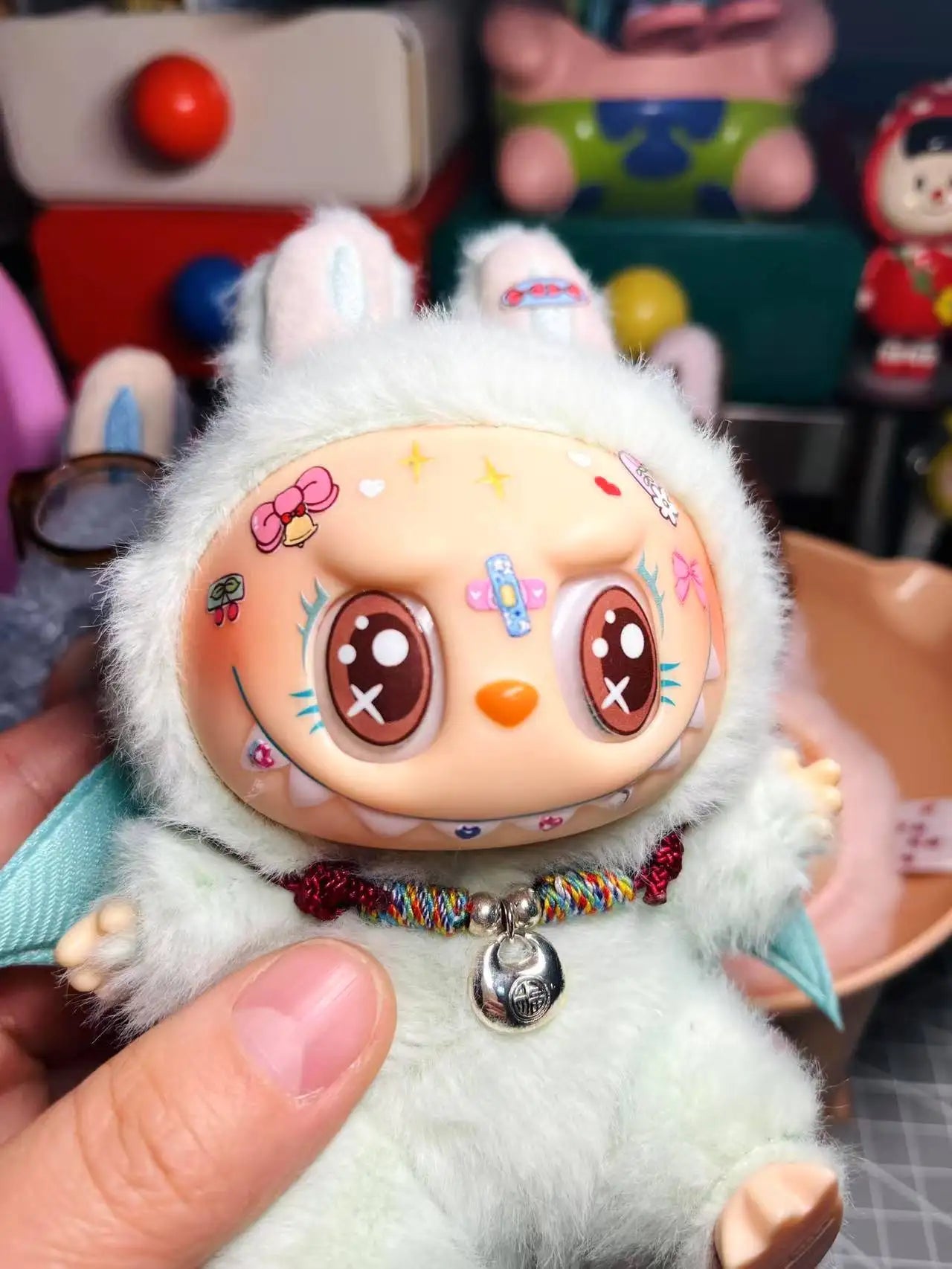 Plush toy with decorative face held by a hand, colorful background