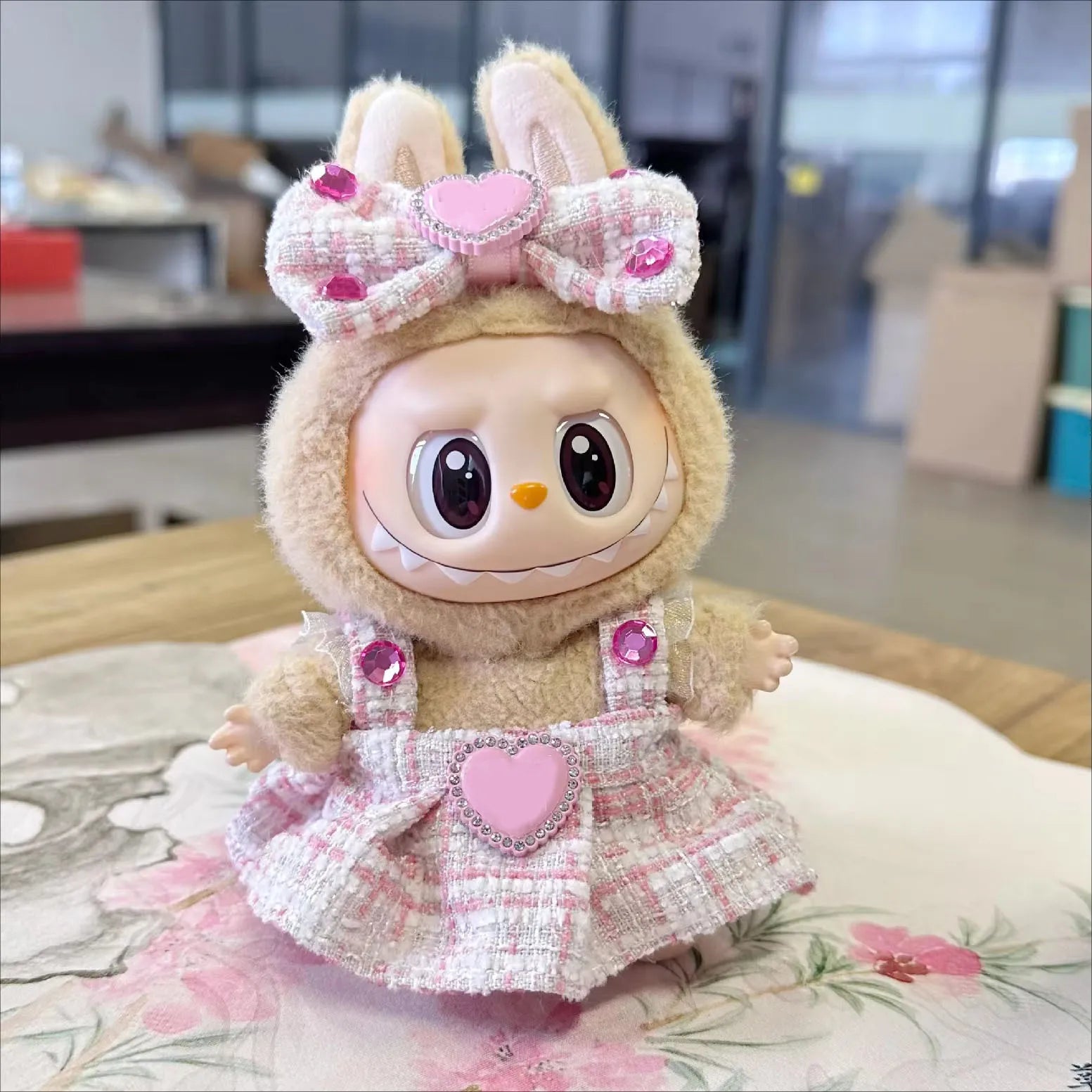 Toy figure with bunny ears and a pink dress on a floral cushion